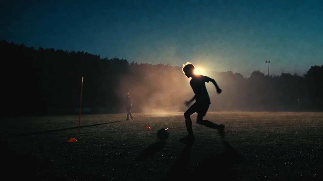 Jeugdspeler dribbelt met de bal in tegenlicht tijdens een avondtraining